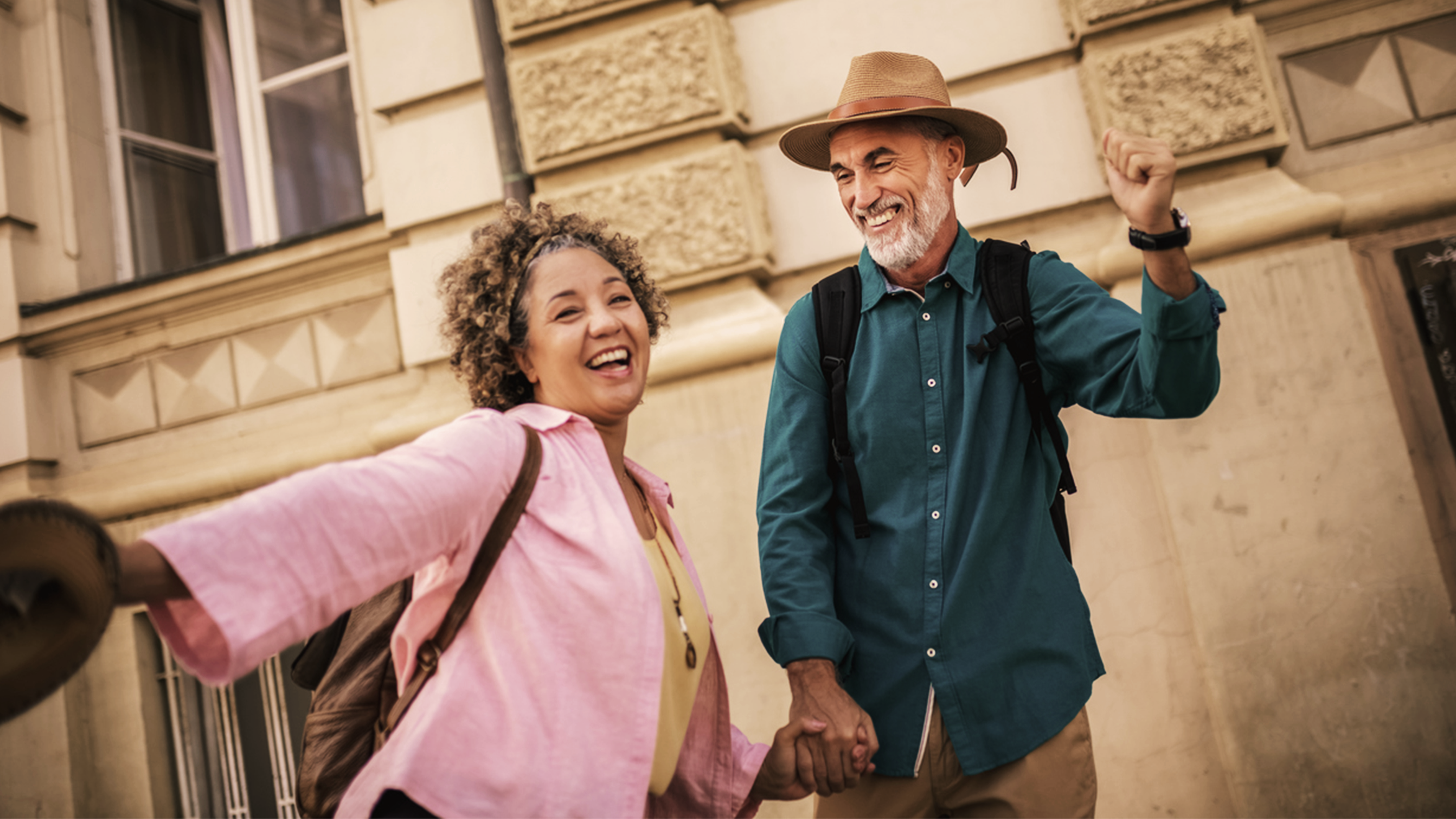 Lady in a pink shirt and man in a green shirt smiling and holding hands.